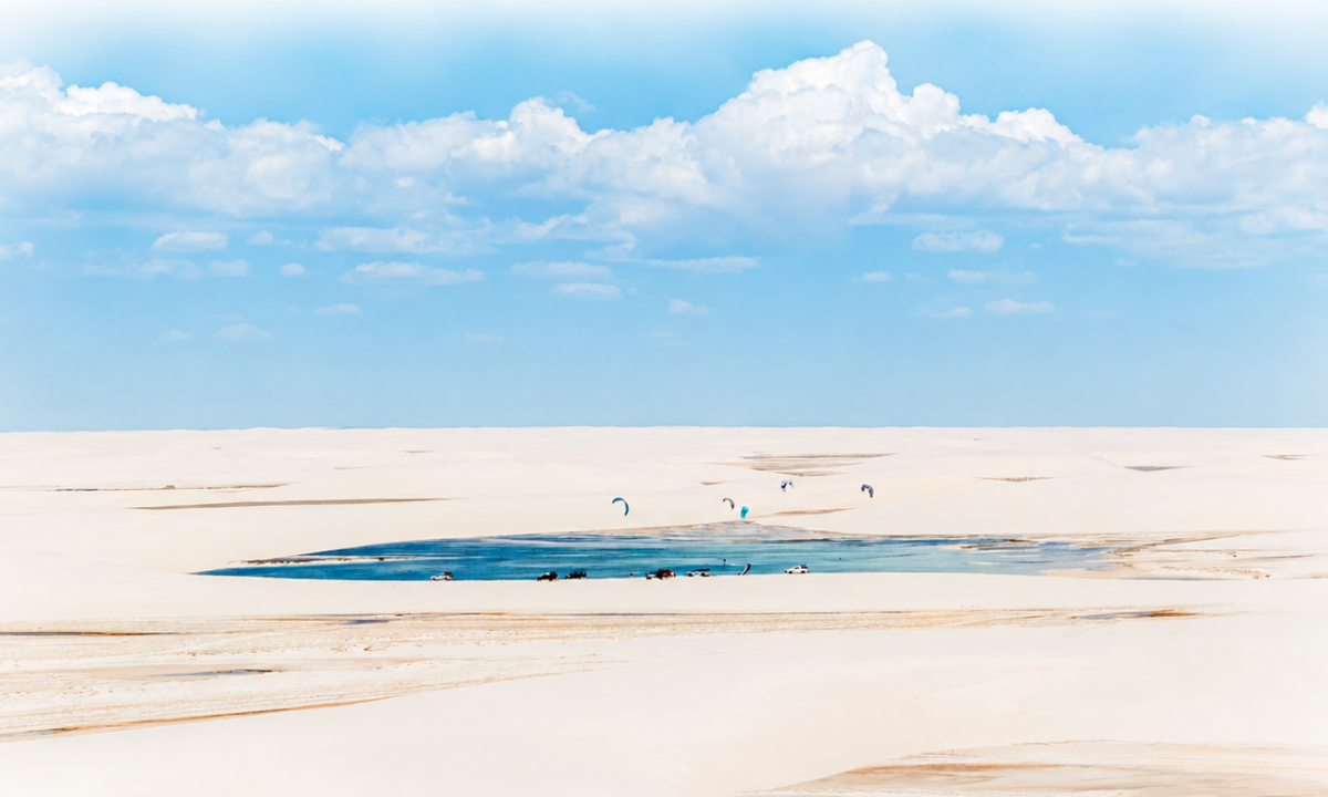 Lagoa azul entre as dunas dos Lençóis Maranhenses, com kites e veículos de apoio